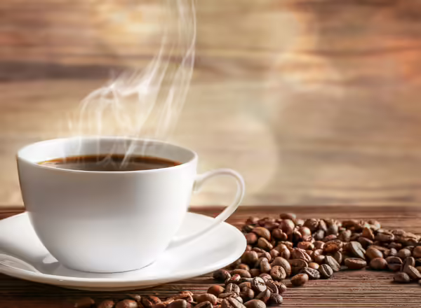 cup of coffee surrounded b coffee beans
