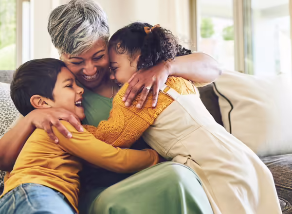smilling grandmother hugs two young grandchildren