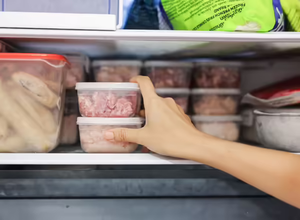 person putting meat into freezer