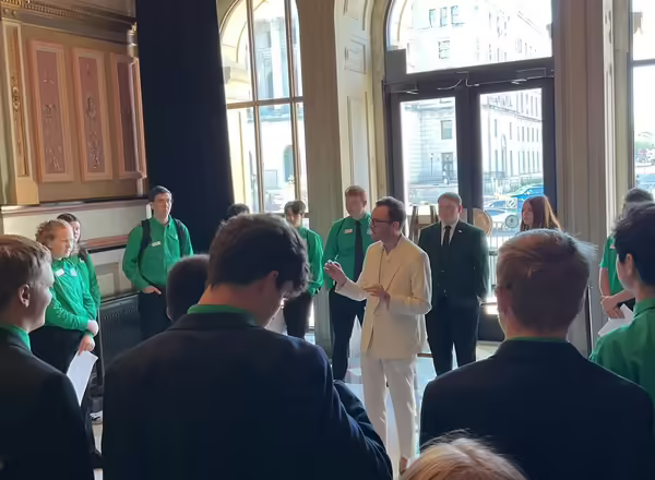 Kevin Carey stands in the middle of youth and adults in Springfield. Others are wearing a black suit or green dress shirts. Kevin is dressed in a white suit.