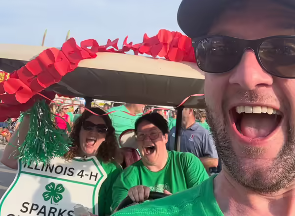 Kevin Carey poses for a selfie with other 4-H staff members who are riding a golf cart