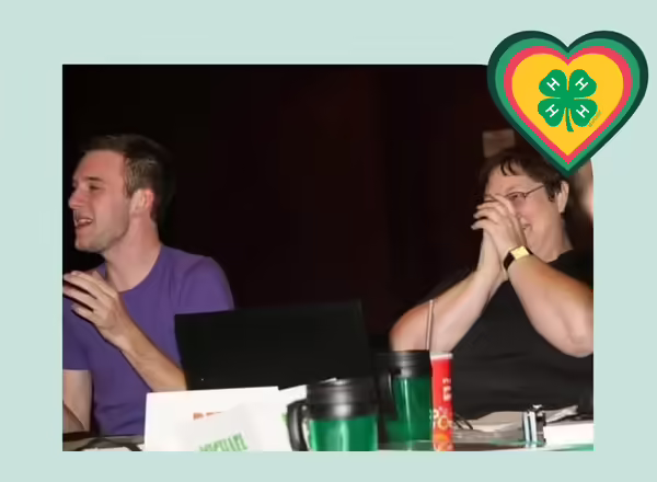 Deb Stocker and Kevin Carey sit at a table when Kevin was on the Youth Leadership Team. They are laughing.