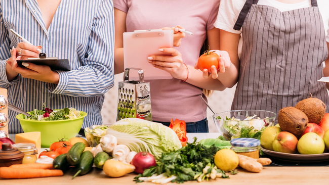 Image of people looking at a variety of food and taking notes