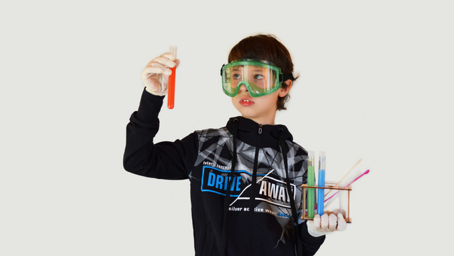 A boy wearing goggles and holding chemistry materials