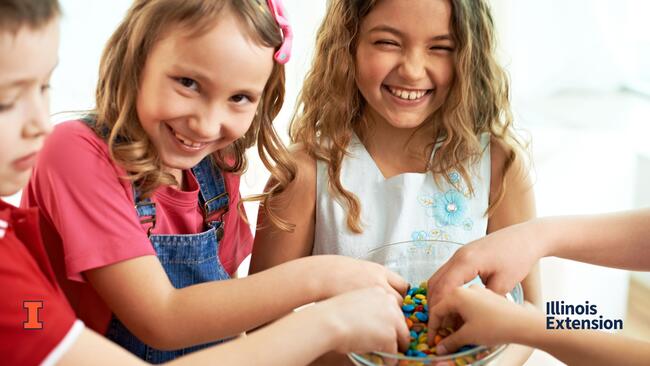 children with hands in a bowl of food