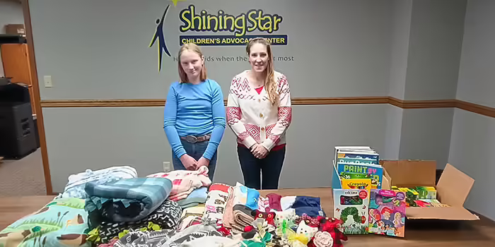 Two people staning behind a table with blankets and boxes of coloring books.