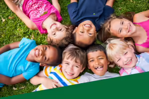 kids laying on the grass looking up at the camera smiling