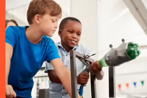 two boys with a homemade plastic bottle rocket on a zip line