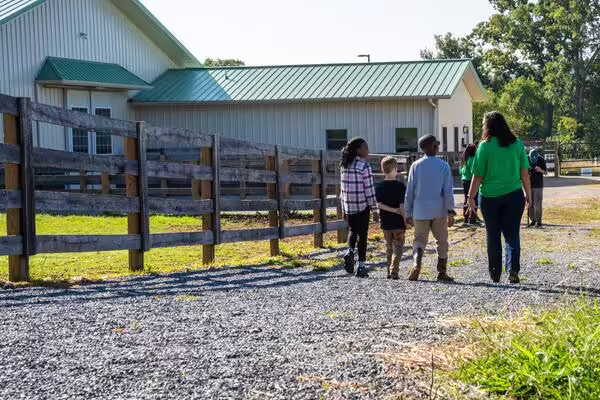 4-H member leads three younger members down a gravel path towards barn