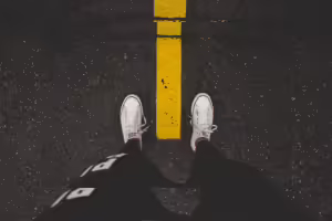 Feet in white canvas shoes on each side of a yellow line