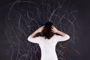 woman in front of chalkboard with hands on head