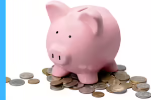 pink piggy bank with loose change laying around its feet