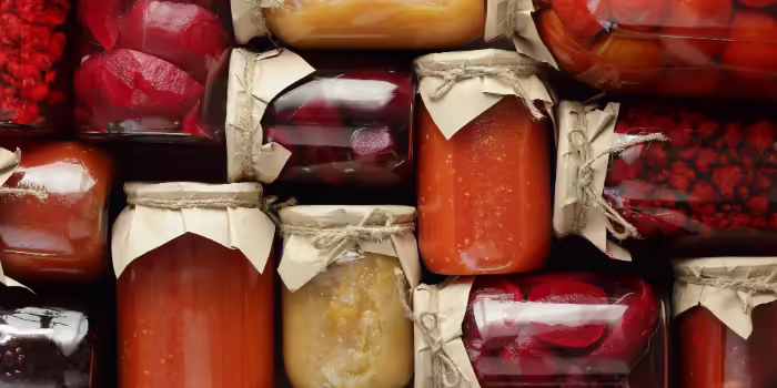 Assorted jars of preserved fruits and vegetables arranged closely together.