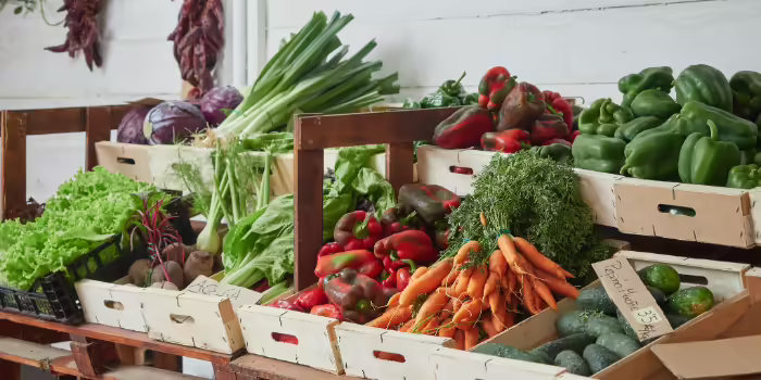 Fresh vegetables displayed in wooden crates at a market stand.