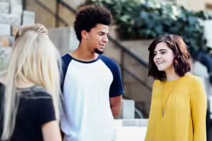 Three teens smiling and interacting outside of school building