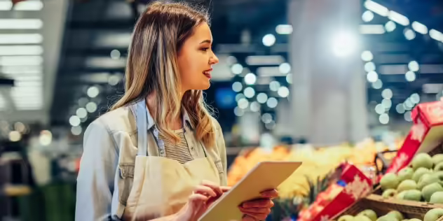 grocery store employee taking inventory of produce