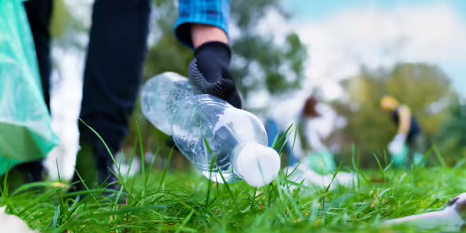 Person picking up a plastic water bottle