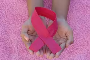 Hands holding pink breast cancer awareness ribbon.