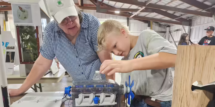 A 4-H member shows a volunteer judge his small engine project