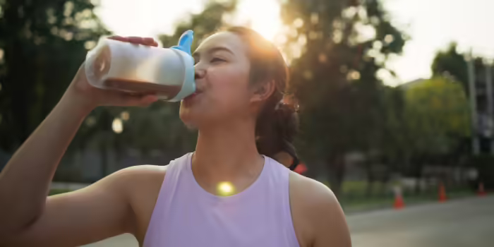 A teen athlete drinking from a water bottle outdoors.