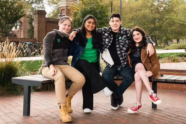 four 4-H friends posing on a park bench