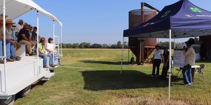 People watching a crop science presentation from a people mover.
