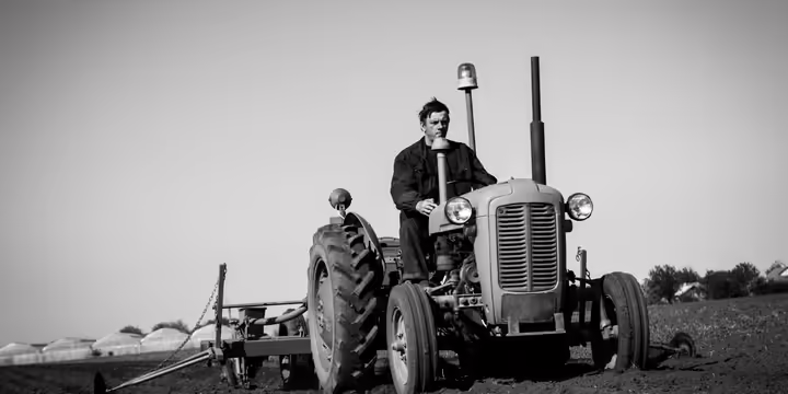 A man driving an old time tractor.
