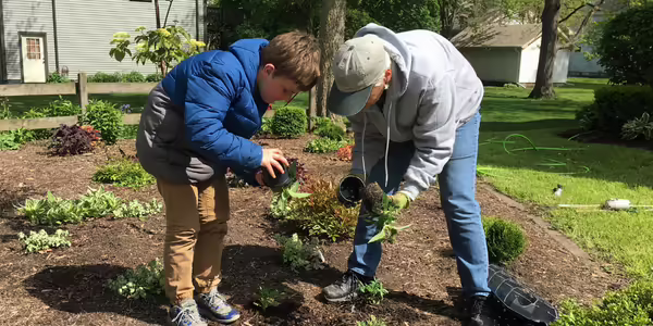 A gardener and a young boy planting flowers.