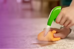spay bottle and cloth scrubbing a stain on a white carpet