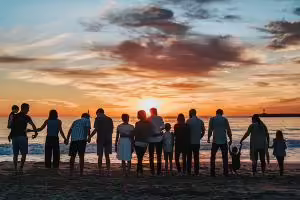 Family and friends of all ages holding hands on beach