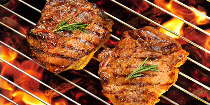 Pork chops on a charcoal grill.