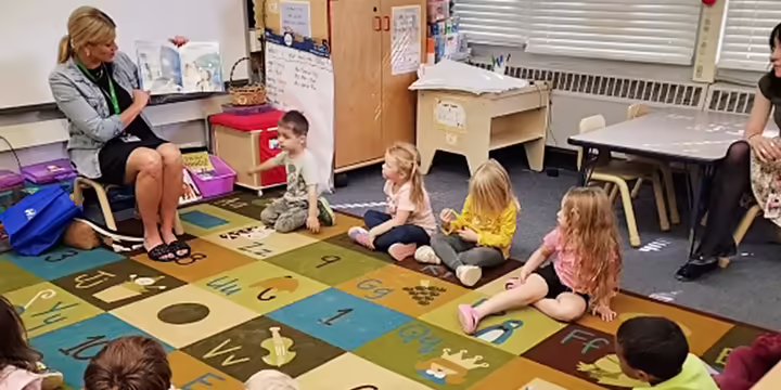 a lady reading a book to pre school children