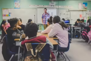Kids sitting in a classroom with a teacher at the front