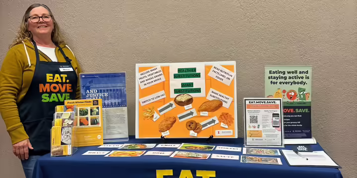 Community Worker standing by booth about healthier substitutions