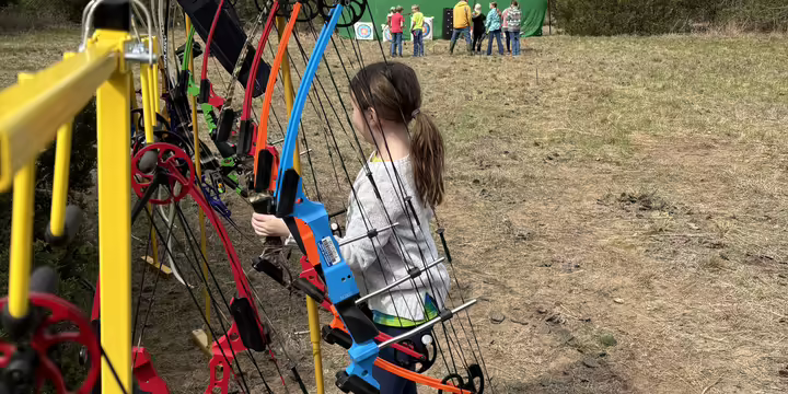 Child holding a bow on an archery range