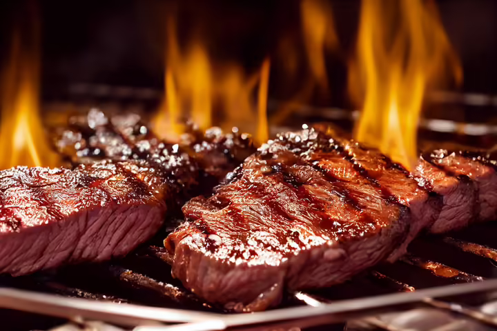 steaks on a flaming hot grill 
