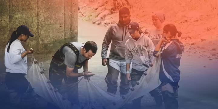 Students standing in a river with a net