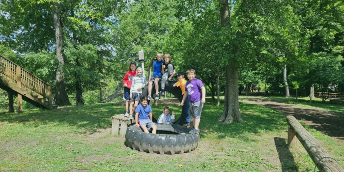 4-H youth outside at a farm posing for a photo on a big tire. 