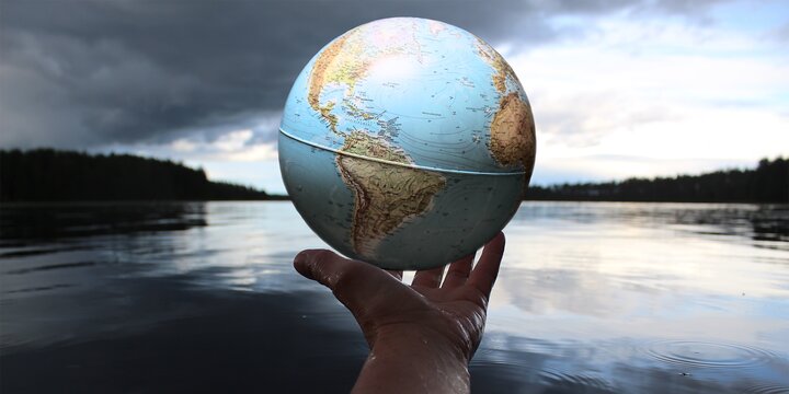 hand holding globe over lake