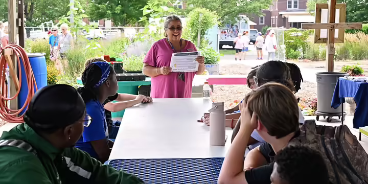 Woman standing and speaking to a group of young adults