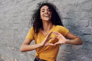 Happy young woman makes a heart with her hands