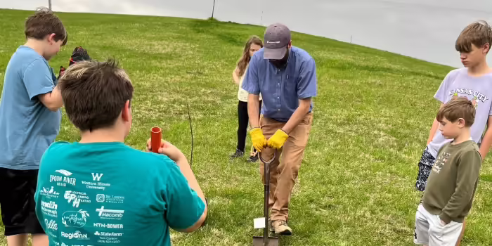 A group of 4-H youth learn how to plant a tree.