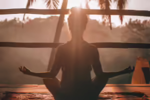 Women meditating in front of sunset