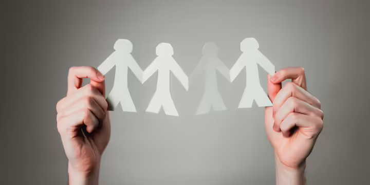 Paper chain of figures held between hands