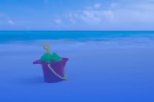 bucket sitting on the sand next to ocean