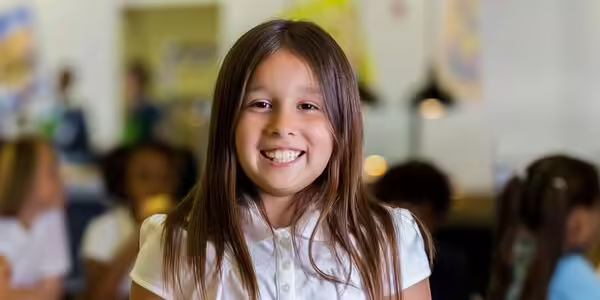 Girl standing in a cafeteria holding a lunch tray.