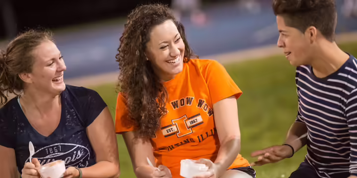 three UIUC students wearing University of Illinois branded clothing