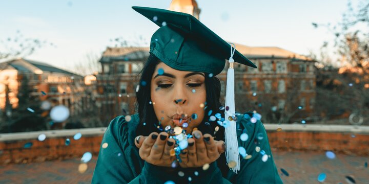 graduate blowing confetti