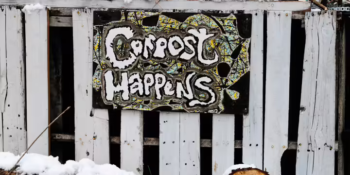 sign on white fence says compost happens