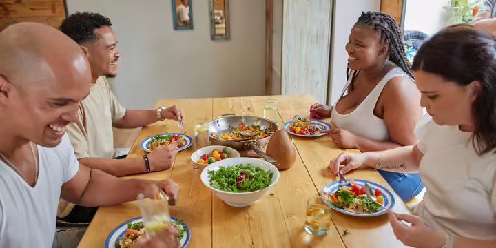 Four people eating salad at a table smiling